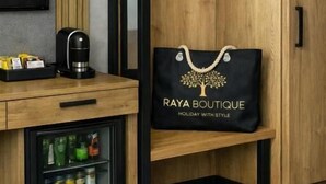 A wooden wardrobe with a black bag labeled 'Raya Boutique' and a coffee machine on a wooden counter. - Raya Boutique (Sunny Beach)