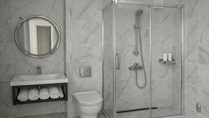 A modern bathroom with a glass-enclosed shower, a toilet, a sink with a mirror, and a towel rack. - Raya Boutique (Sunny Beach)