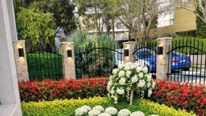 A landscaped pathway with a curved design, bordered by neatly trimmed hedges and flowering plants. - Raya Boutique (Sunny Beach)
