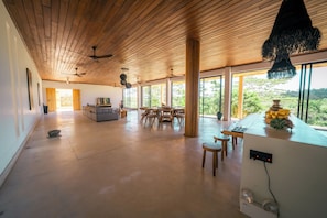 Un interior espacioso con techo alto, ventanas grandes y una zona de comedor.