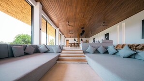 A modern interior with a wooden ceiling, large windows, and a central staircase leading to a dining area. - The 180 villa (Galle)
