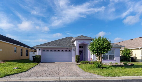 A single-story house with a paved driveway, a garage, and a small tree in the front yard. - Pelicans Landing - Three Bedroom House, Sleeps 6 (Davenport)