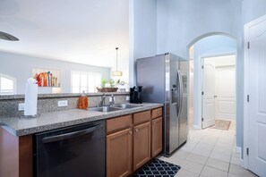 A modern kitchen with granite countertops, stainless steel appliances, and wooden cabinets. - Pelicans Landing - Three Bedroom House, Sleeps 6 (Davenport)