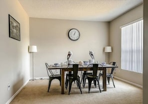 A dining room with a round table, four chairs, two wall-mounted lamps, a clock, and a window with blinds. - Sunset Ridge Villa - Five Bedroom House, Sleeps 10 (Davenport)