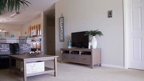 Un salon avec un téléviseur, une table basse et une bibliothèque.