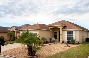 A two-story house with a beige exterior, a brown roof, and a front porch. - Sunset Ridge Villa - Five Bedroom House, Sleeps 10 (Davenport)