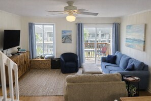 Un salon équipé d’un téléviseur, d’un canapé, d’un fauteuil et d’un ventilateur de plafond.