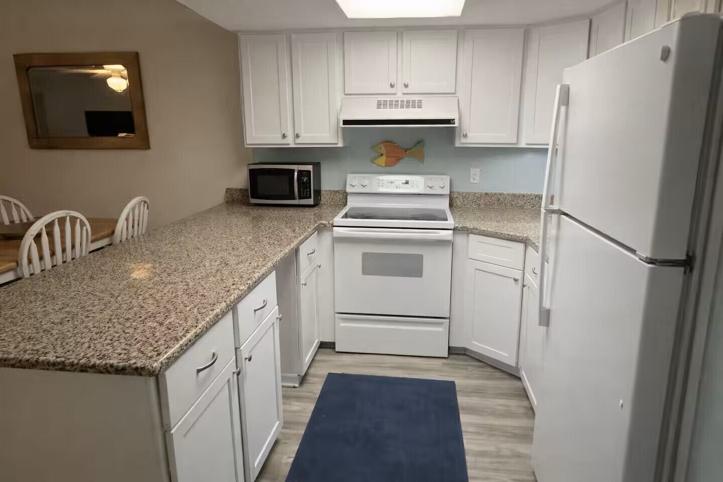 A compact kitchen with white cabinets, a microwave, an oven, and a refrigerator.
