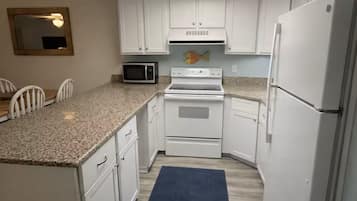 A compact kitchen with white cabinets, a microwave, an oven, and a refrigerator.