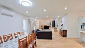 Una sala moderna con un sofá, televisión y comedor con sillas y una mesa.
