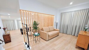 Una sala de estar moderna con un sofá color beige, un panel de madera y una planta en maceta.
