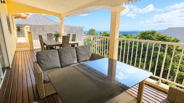 Un balcone con divano, tavolo e sedie, con vista panoramica.