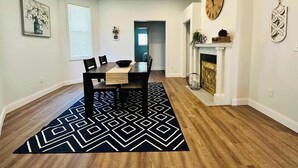 A dining area with a wooden table, chairs, a black and white rug, a fireplace, and wall art. - Beautiful 2 Bedroom Apartment - Easy City Access (Pittsburgh)