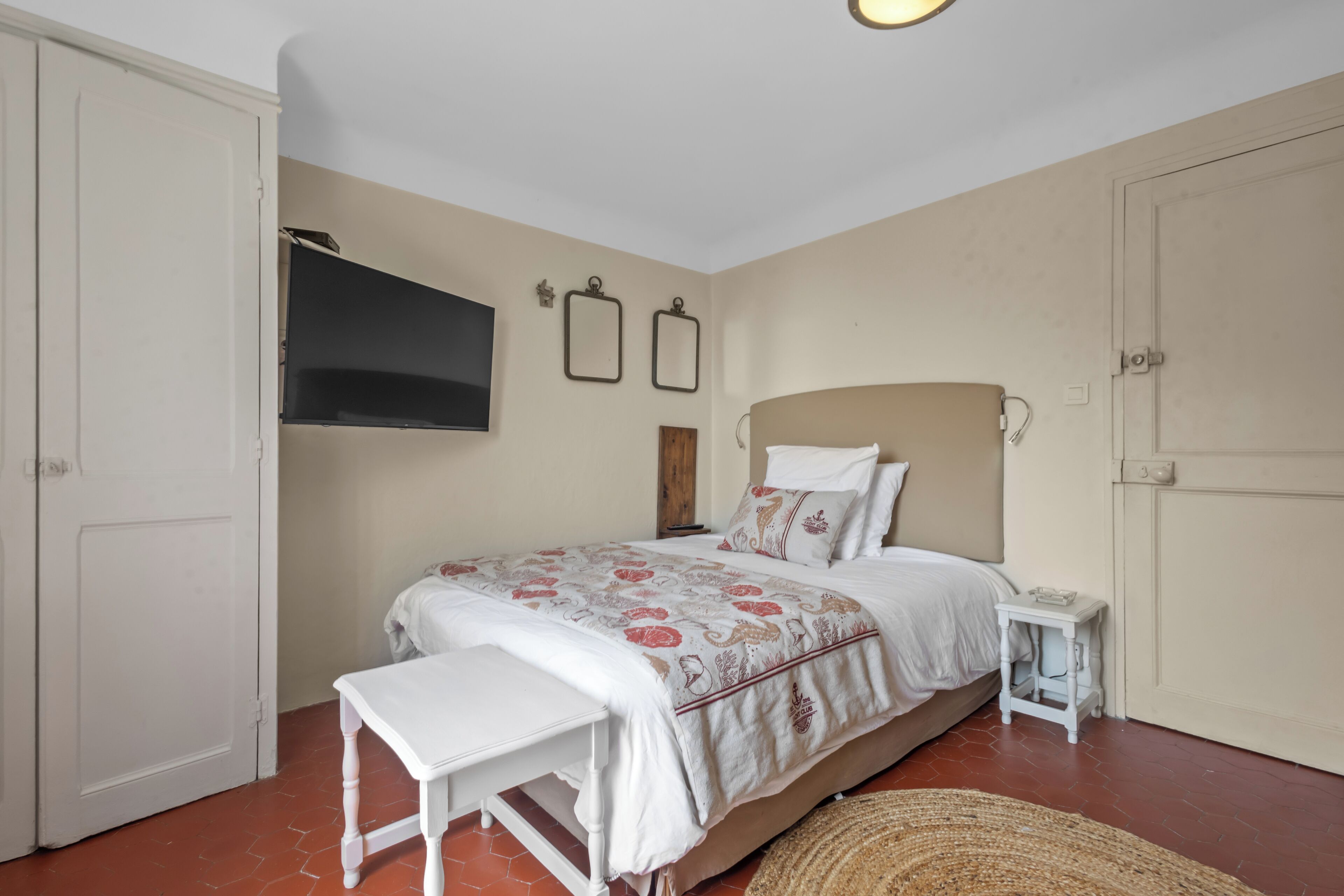 Une chambre à coucher avec un lit, une table de chevet et un téléviseur fixé au mur.