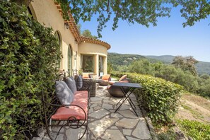 An outdoor patio with stone flooring, wicker furniture, and a view of a hillside.