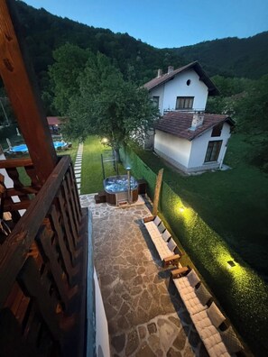 Un patio con suelo de piedra, mobiliario de madera y un jacuzzi.
