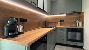 A modern kitchen with a wooden countertop, stainless steel appliances, and light-colored cabinets.