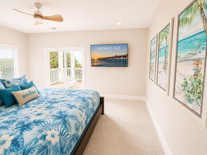 Un dormitorio con una cama, ventilador de techo, vista al exterior y un cuadro de Emerald Isle.