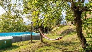 Ein Swimmingpool, eine Hängematte und Bäume in einem Garten.