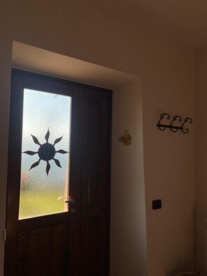 A door with a frosted glass panel featuring a sun design, a dark wooden door, and a wall-mounted decorative item.
