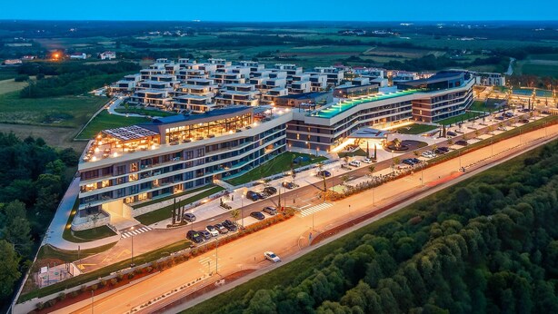 Un hotel moderno con diversi piani, un'area parcheggio e una piscina.