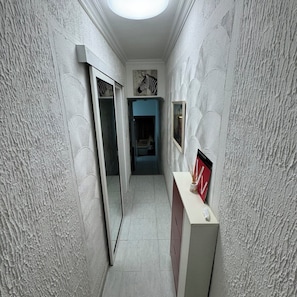 A narrow hallway with textured walls, a mirror, a framed picture, and a cabinet. - Relaxation, comfort, and unforgettable views (Costa Adeje)