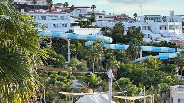 A coastal resort with a pool area, palm trees, and a view of nearby buildings. - Relaxation, comfort, and unforgettable views (Costa Adeje)