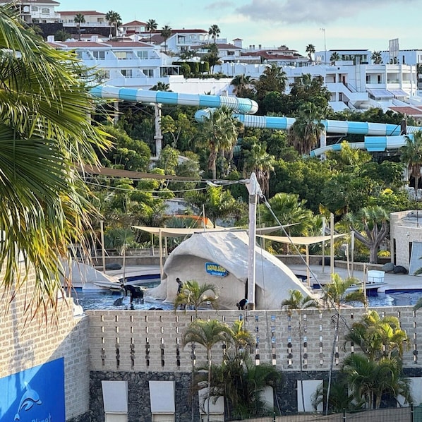 A coastal resort with a pool area, palm trees, and a view of nearby buildings. - Relaxation, comfort, and unforgettable views (Costa Adeje)