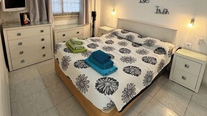 A bedroom with a bed, a ceiling fan, a bedside table, a nightstand, a TV, and a window with curtains. - Relaxation, comfort, and unforgettable views (Costa Adeje)