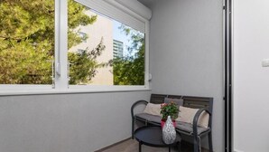 A balcony with a sofa, a small round table, and a potted plant. - Leora Deluxe Apartment  (Split)