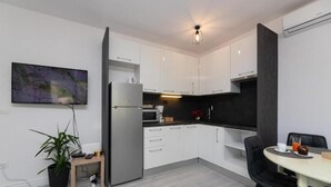 A modern kitchen with white cabinets, a microwave, and a dining area with a table and chairs. - Leora Deluxe Apartment  (Split)