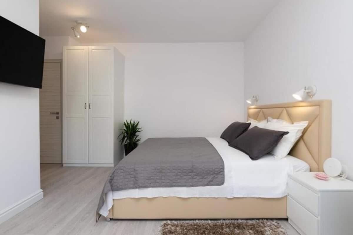 A bedroom with a bed, bedside table, lamp, wardrobe, and a small plant.