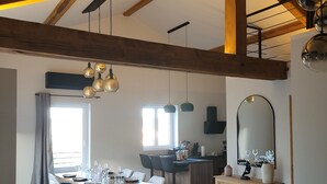 Un vaste espace de vie comprenant un coin repas avec une table pour six personnes, un canapé et une cuisine avec un bar.