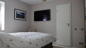 Ein Schlafzimmer mit einem Bett, einem gerahmten Bild an der Wand, einem Fernseher und einer Tür.