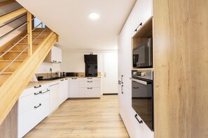 Eine moderne Küche mit Holzboden, weißen Schränken und einer eingebauten Mikrowelle.