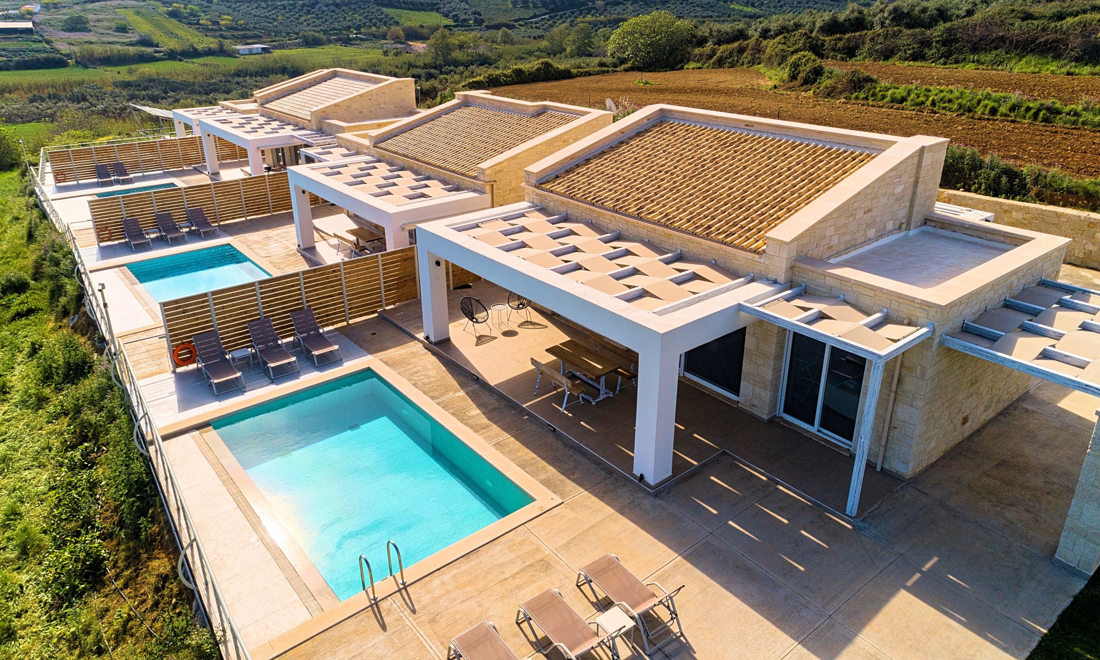 Zona de piscina al terrat amb diverses gandules, una piscina i una estructura de pèrgola.