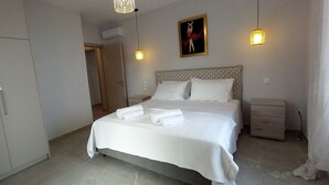 A bedroom with a bed, bedside tables, a wardrobe, and a painting on the wall. - Stone Villa Vasiliki Private Pool & Sea View (Corfu)