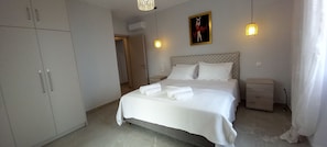 Ein Schlafzimmer mit Bett, Nachttischen, einem Kleiderschrank und einem Bild an der Wand.