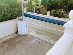 A gated entrance with a metal barrier, a white wall, and a concrete floor. - House Cala Playa Denia (Denia)