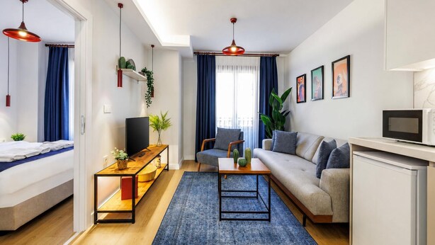 Ein modernes Wohnzimmer mit Sofa, Couchtisch, Fernseher und Essbereich mit Mikrowelle.
