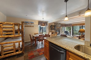 A kitchen with a granite countertop, wooden cabinets, and a built-in dishwasher. - Quiet Walk to Slopes Condo 660 (Mammoth Lakes)