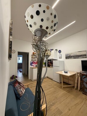 A modern living room with a unique spherical lamp, a blue sofa, and a kitchen in the background. - MiniHome Turin (Torino)