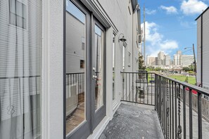 Un immeuble résidentiel doté d’un balcon, de grandes fenêtres et offrant une vue sur le paysage urbain.