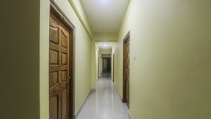 A corridor with wooden doors, a tiled floor, and a light fixture on the ceiling.