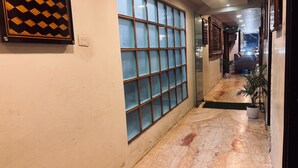 A hallway with a tiled floor, a large window with a grid pattern, and a potted plant.