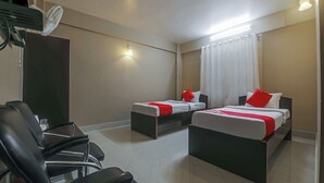 A hotel room with two beds, a desk, a chair, and a ceiling fan.