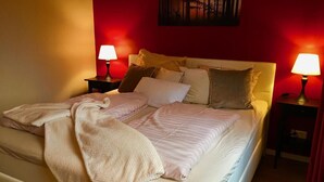 A bed with a white comforter and pillows, two bedside tables with lamps, and a painting on the wall. - Vacation apartment Gute Zeit Hahnenklee (Goslar)