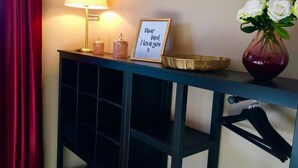 A room with a blue console table, a lamp, a framed sign, a vase with flowers, and a basket. - Vacation apartment Gute Zeit Hahnenklee (Goslar)