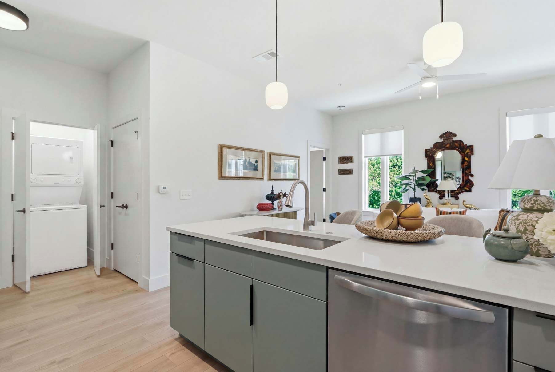 A modern kitchen with a central island, a built-in dishwasher, and a ceiling fan.