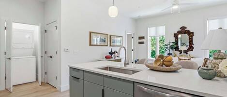A modern kitchen with a central island, a built-in dishwasher, and a ceiling fan.